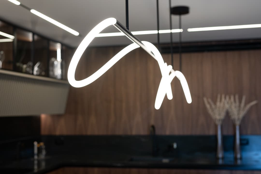 Sinuous white LED pendant loop over fluted kitchen island