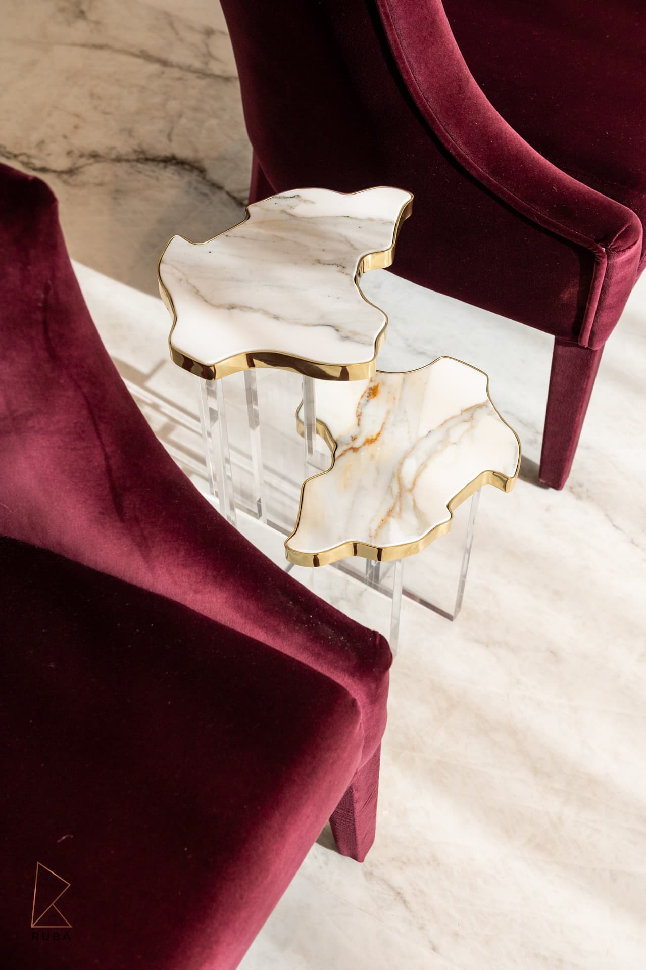 Marble and gold side table between burgundy velvet chairs