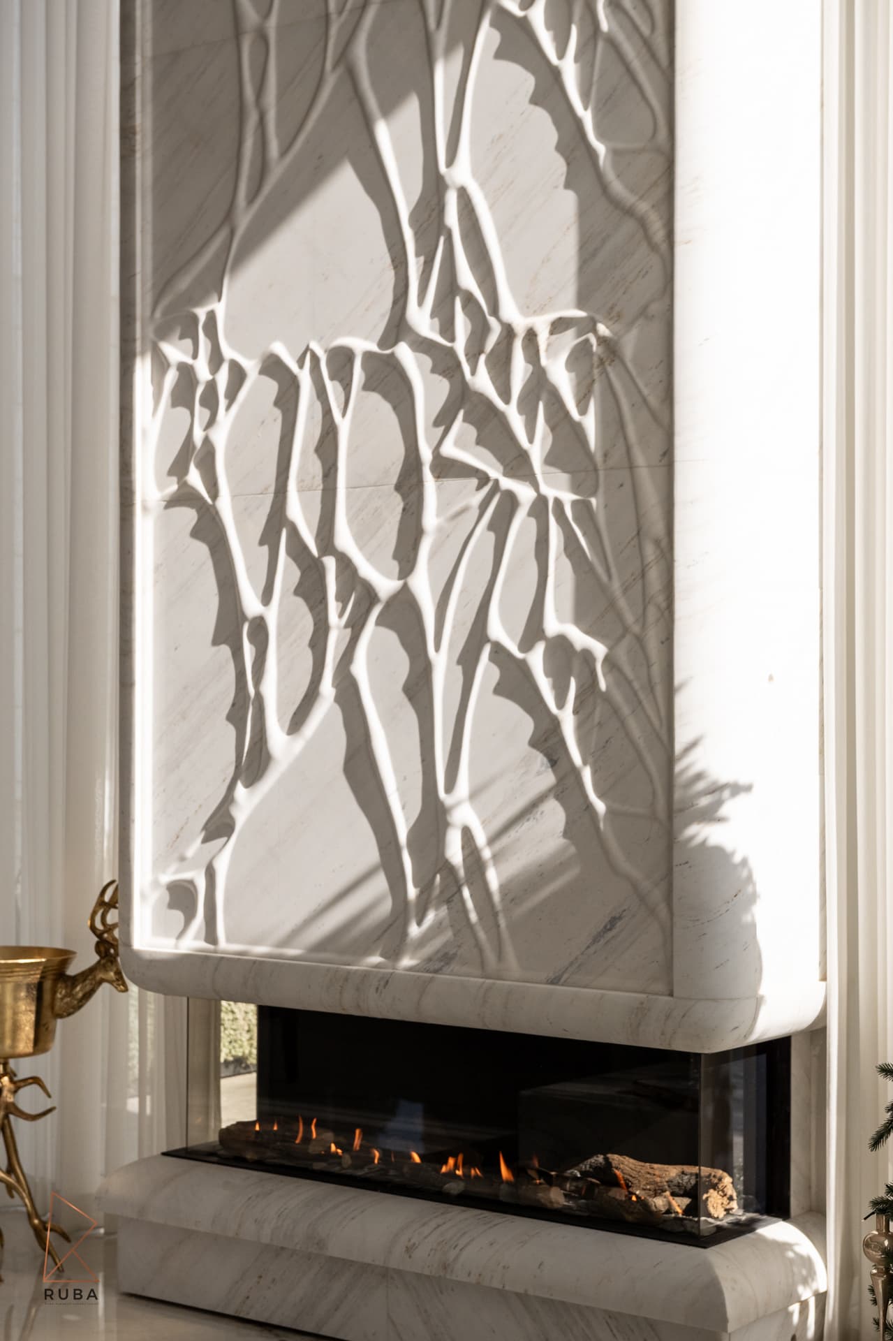 Backlit marble tree sculpture panel above linear fireplace