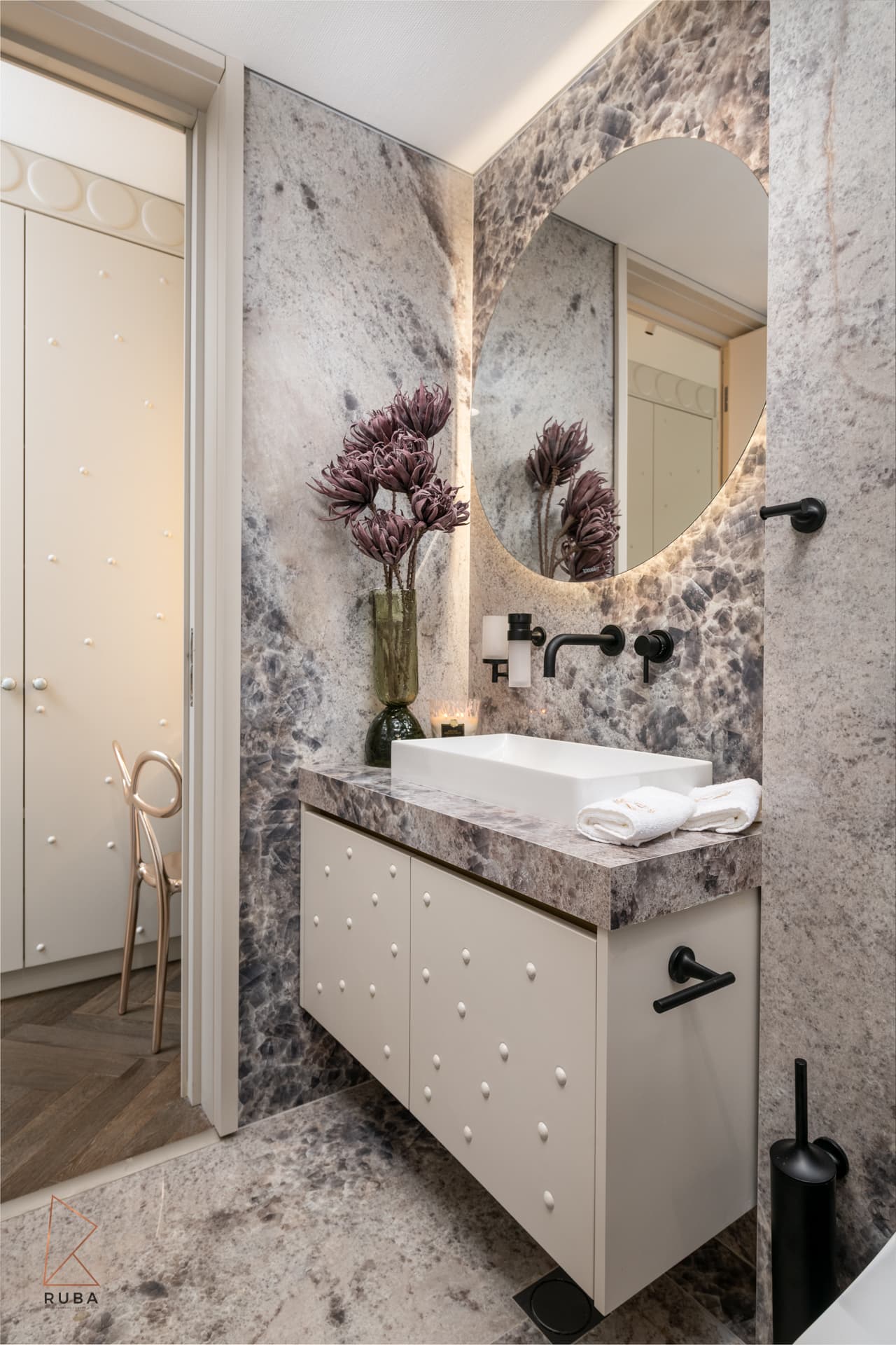 Backlit round mirror over dramatic grey-veined marble vanity