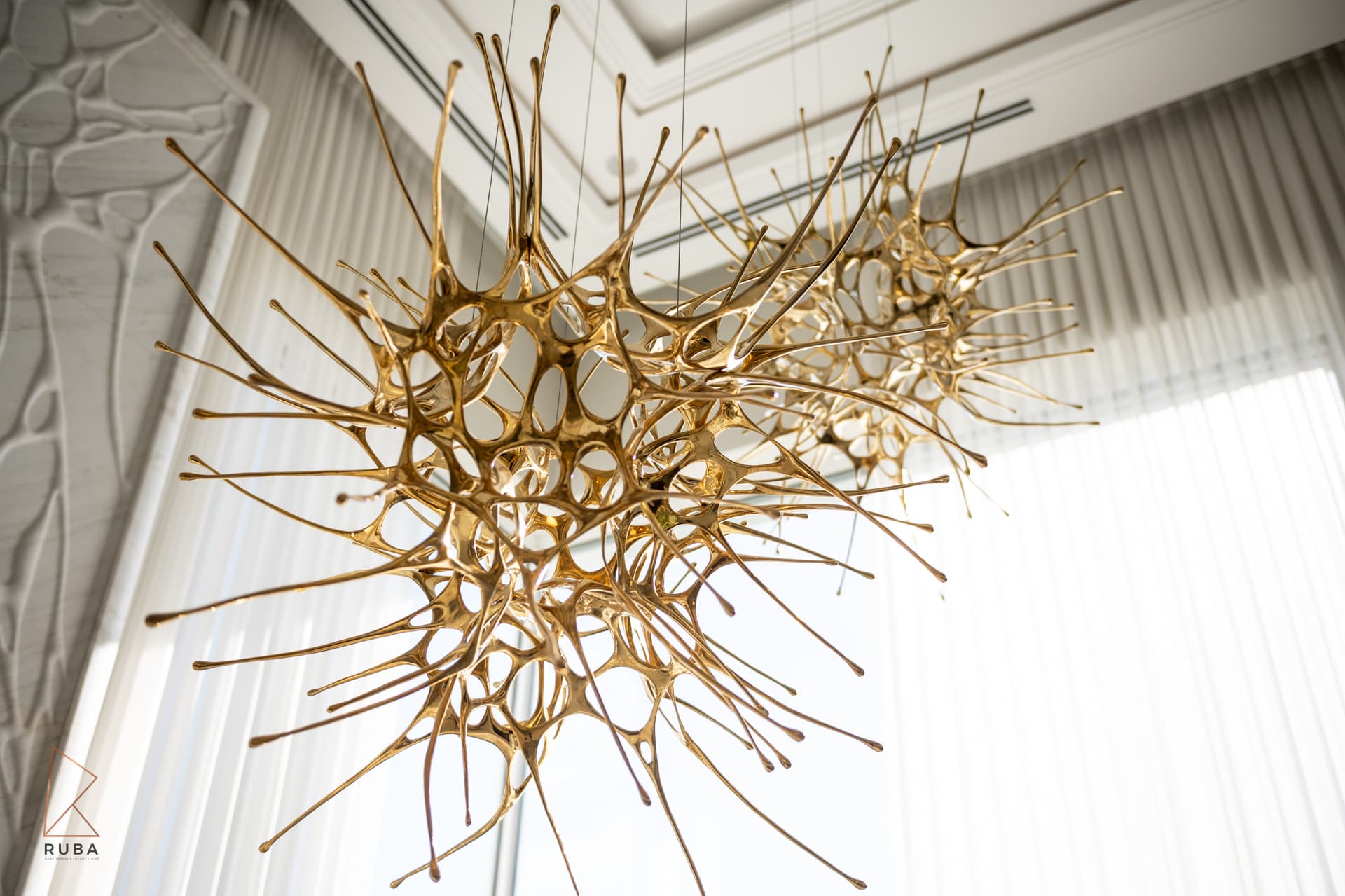 Sculptural gold organic chandelier against coffered ceiling