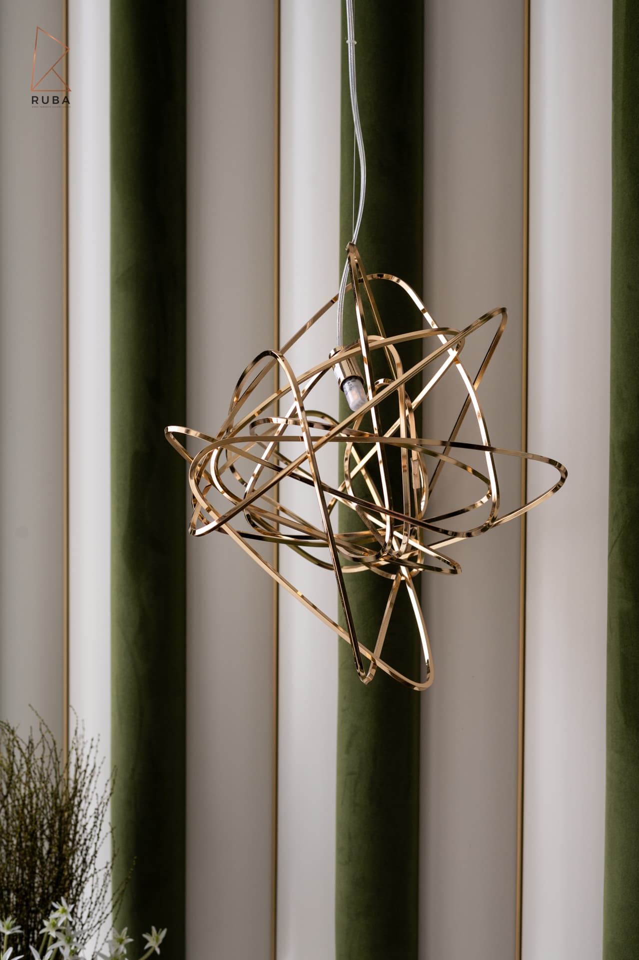 Gold chain-link cascading wall sconce beside floor-to-ceiling glass