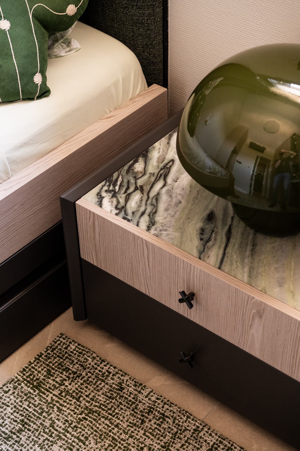 Bleached oak nightstand with marble-lined drawer and green glass lamp