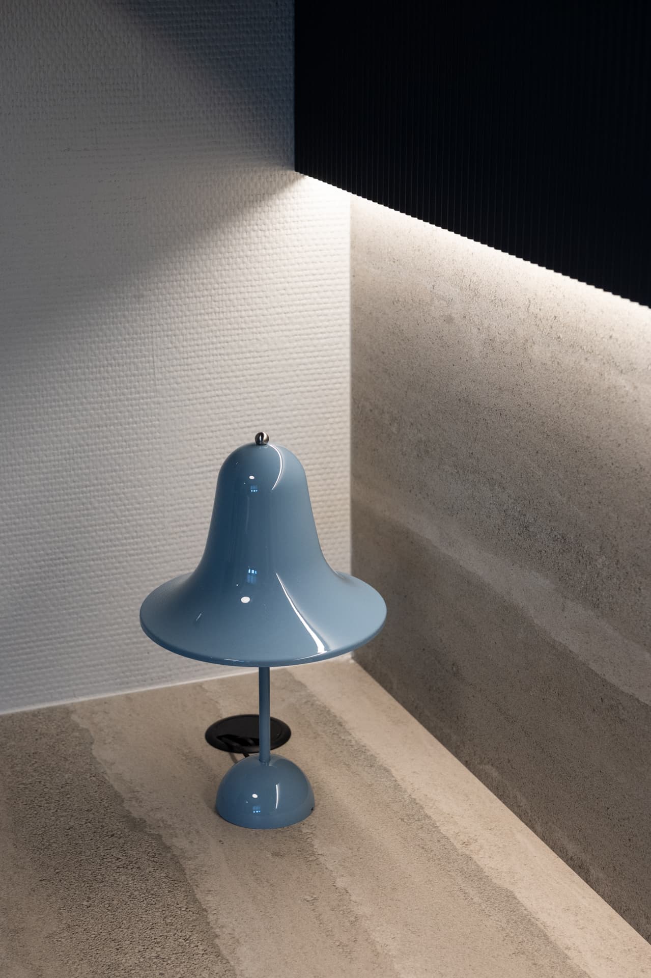 Pantop table lamp in dusty blue on travertine step with LED strip