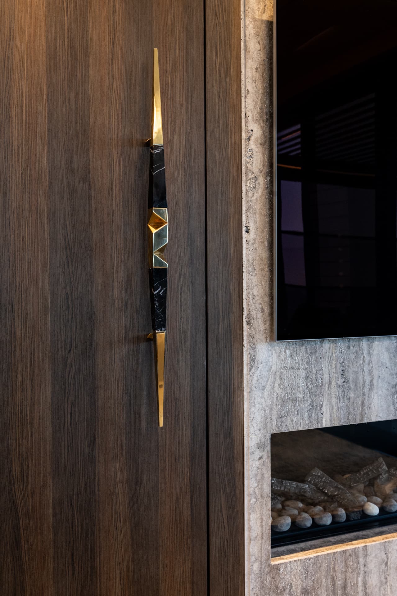 Gold-and-black-marble spear-form door pull on walnut veneer panel