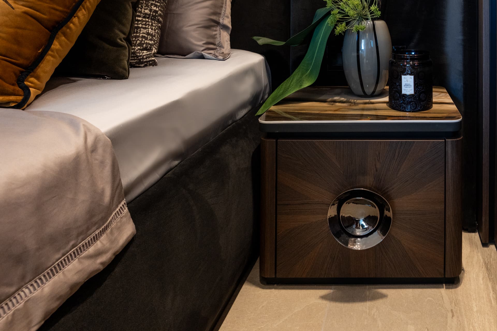 Sunburst walnut nightstand with chrome orbit handle and silk bedding