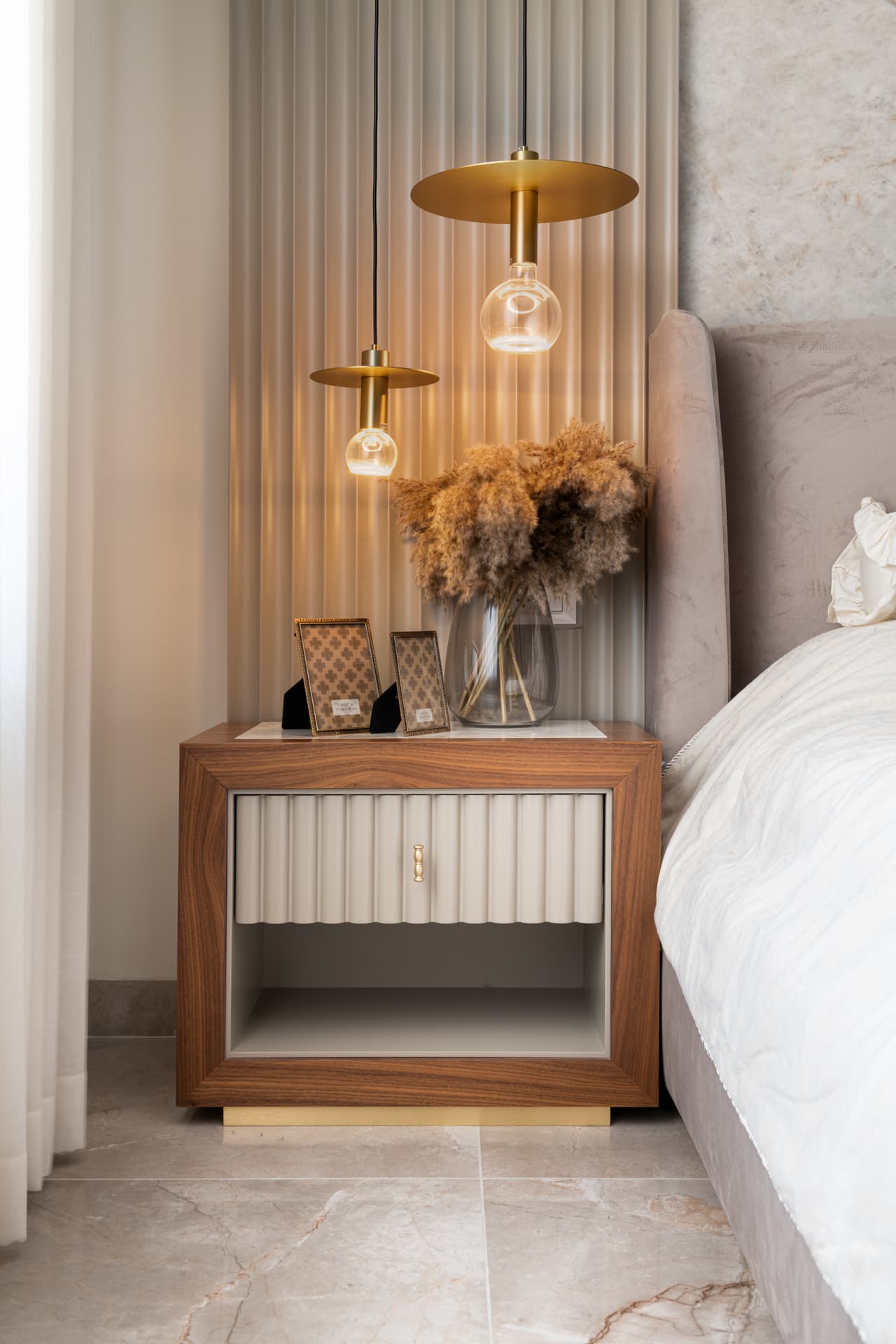 Grey tweed armchair with chrome ring detail beside amber glass vase