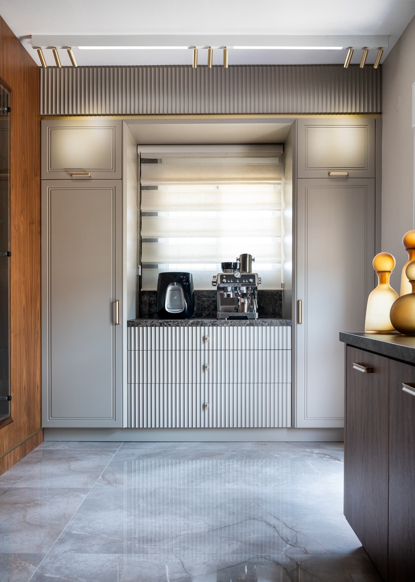 Fluted cream wall panel with gold pendant drop beside walnut